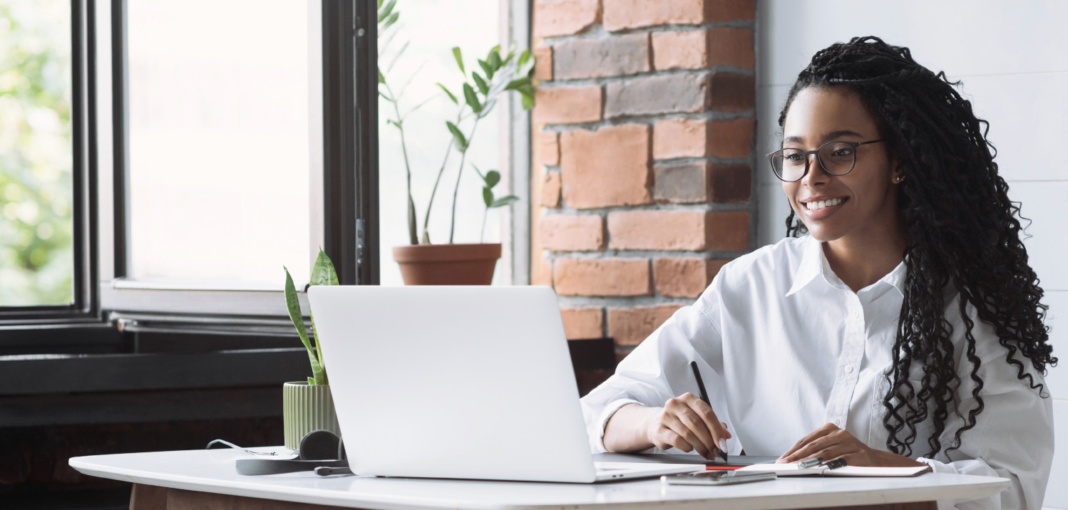 Young african-american woman smiling writing on tablet watching laptop screen