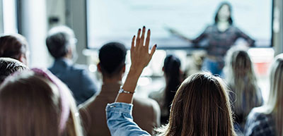 Conference attendee with hand raised