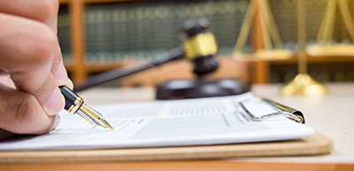 signing document with gavel and scales of justice in background